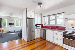 Una cocina moderna con electrodomésticos de acero inoxidable, lavavajillas y un salpicadero rojo.