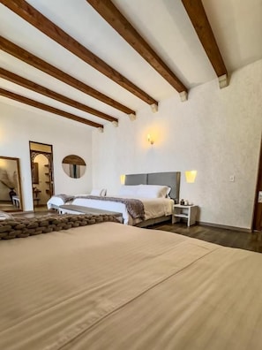 Un dormitorio con una cama grande, vigas de madera, una mesita de noche y una lámpara de pared.