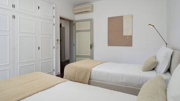 A bedroom with two beds, a wardrobe, and a wall-mounted air conditioner.