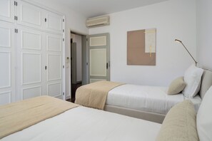 Een slaapkamer met twee bedden, een kledingkast en een wandairconditioner.