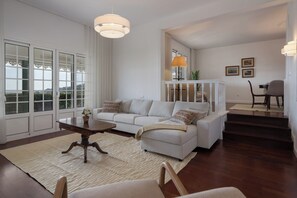 A living room with a sofa, coffee table, and a staircase leading to another level. - Moradia Padre Laurindo – Funchal Bay Views (Funchal)