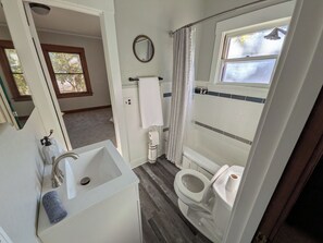 Een badkamer met een wit wastafel, toilet en douchegedeelte.