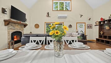 Un coin repas avec une cheminée, un téléviseur et une vue sur l’extérieur.