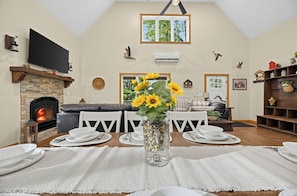Uma sala de jantar com lareira, televisão e vista para o exterior.