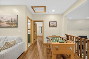 Quarto com sofá, mesa de futebol e uma pintura na parede.