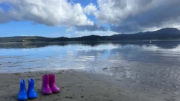 A beach with footprints leading to a pair of blue and pink boots.