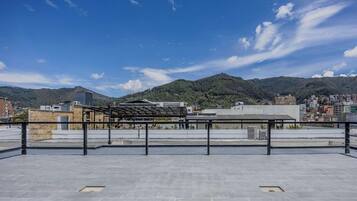 A rooftop terrace with a view of a cityscape and mountains.