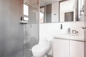 A modern bathroom with a glass shower enclosure, a white toilet, and a vanity with a mirror. - NOK Cozy 2 BR at Usaquen (Bogotá)