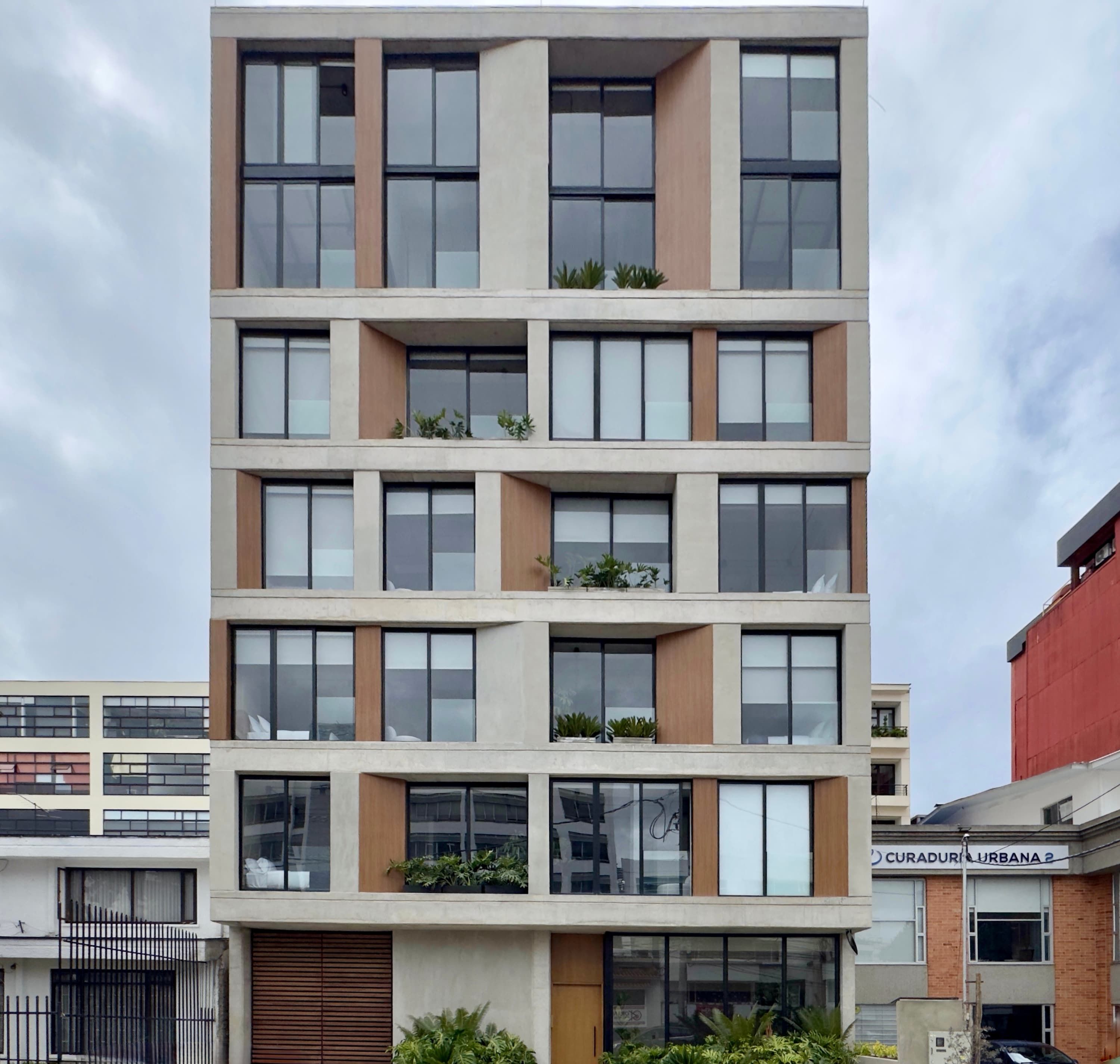 Un edificio de varios pisos con balcones, ventanas amplias y fachada plana.