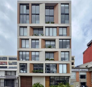 Un immeuble à plusieurs étages, doté de balcons, de grandes fenêtres et d’une façade plane.