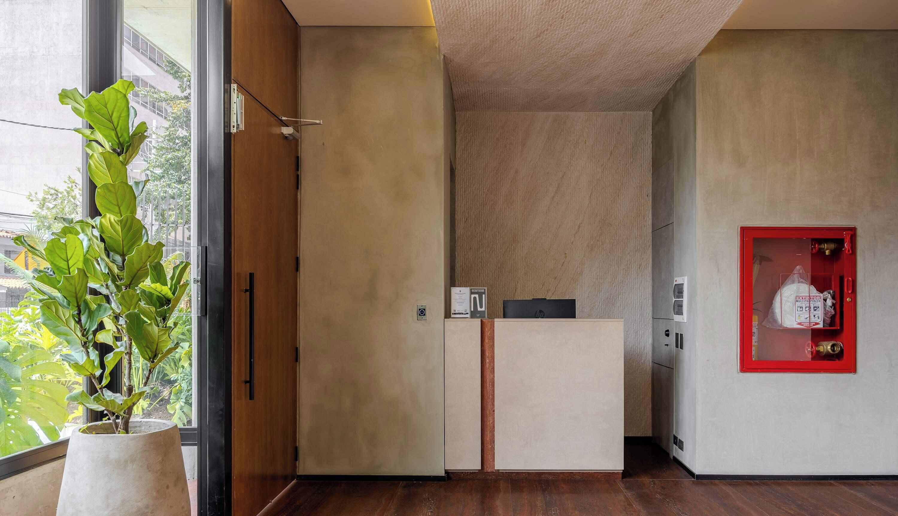 Un interior moderno con un armario de madera, un extintor rojo y una planta en maceta junto a una ventana.