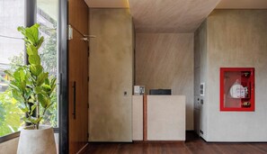 Interior moderno com um armário de madeira, uma caixa de segurança contra incêndio vermelha e uma planta em vaso perto de uma janela.