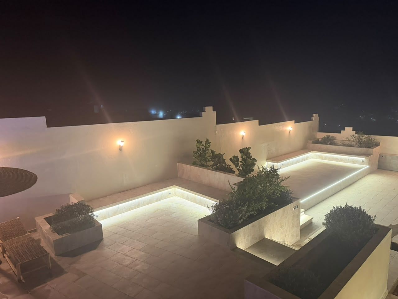 Une terrasse sur le toit dotée d’une piscine rectangulaire, de jardinières et d’un éclairage d’ambiance.