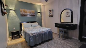Un dormitorio con cama, mesitas de noche, cómoda, espejo e iluminación en la pared.