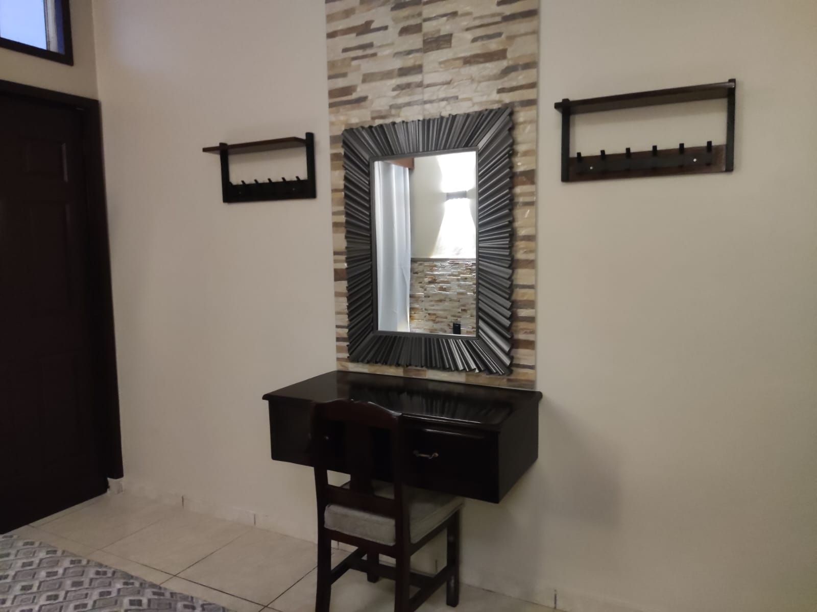 Un baño con tocador, espejo y perchero para toallas.