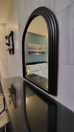 Una habitación con una cama, un cuadro y un espejo en la pared.