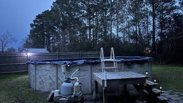 A small outdoor structure with a table and chairs, a ladder, and a propane tank.