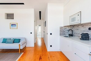 A modern kitchen with white cabinets, a microwave, and a coffee machine. - Urban Haven 2BR Modern Retreat (Lisbon)