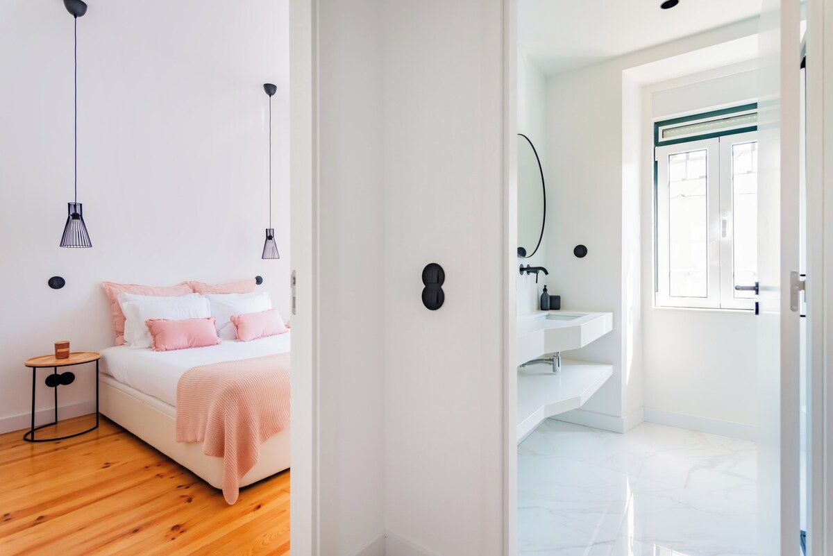 A bedroom with a bed, bedside table, and hanging pendant lights.