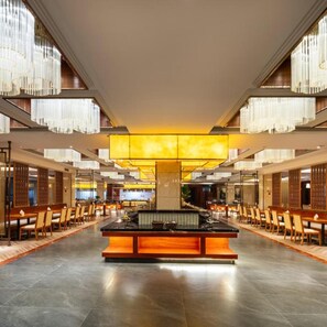 Um hall amplo com balcão de recepção central, pé direito alto e lustres modernos.