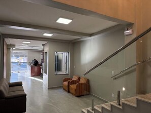 Een moderne lobby met een receptiebalie, een zithoek en een trap.