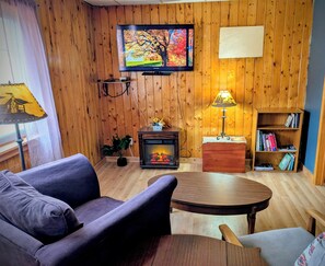 A cozy living room with a television, a fireplace, a bookshelf, and a comfortable seating area.