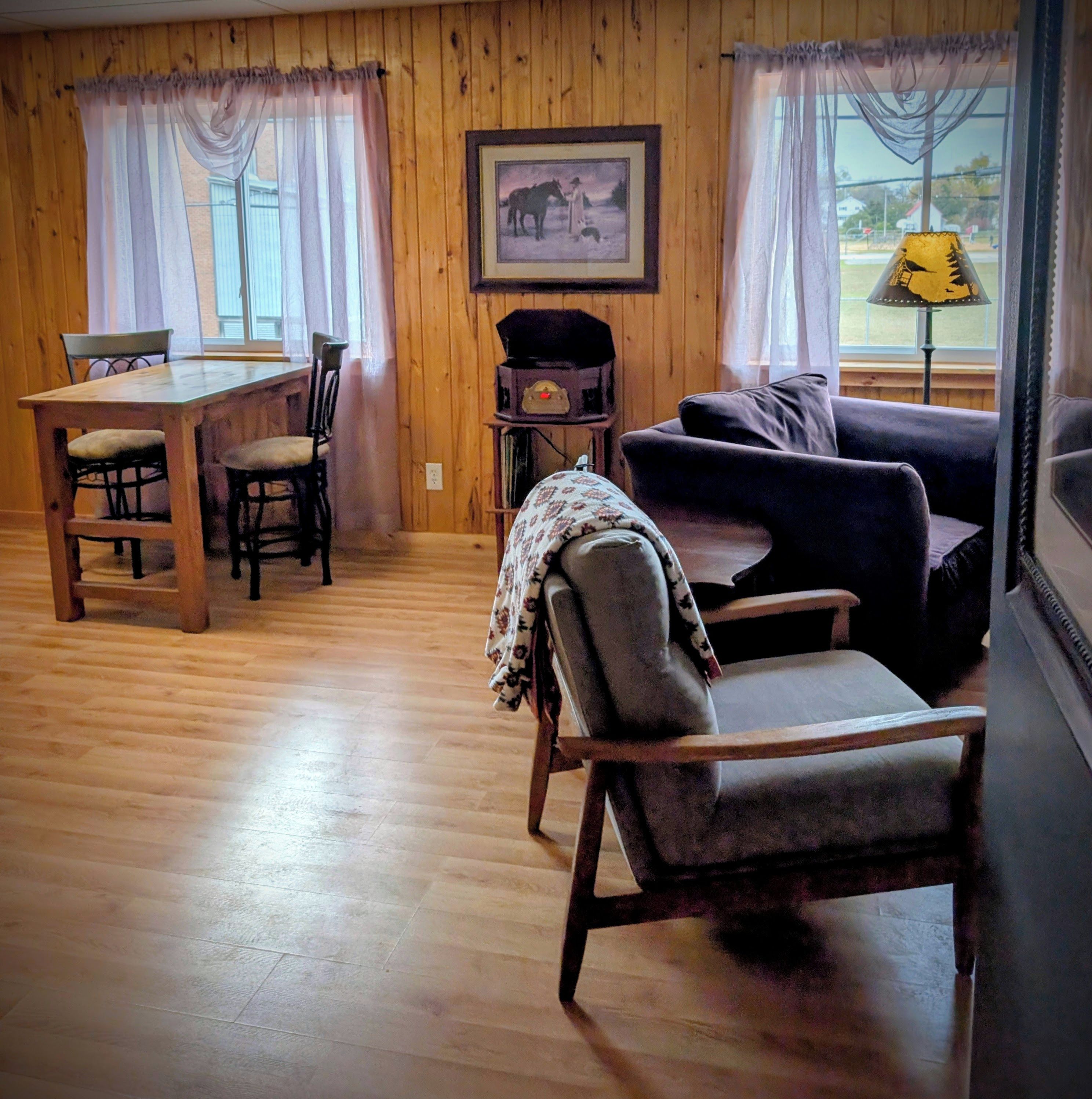 Une pièce avec un plancher en bois, une table à manger avec des chaises, un canapé et une lampe.