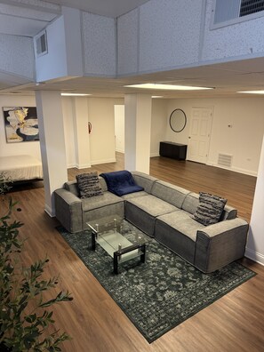 A modern living room with a sectional sofa, a glass coffee table, and a patterned rug. - Family Sized Apt. — in the Heart of Hyde Park ! (Chicago)