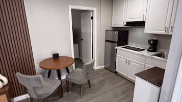 A compact kitchen with white cabinets, a built-in oven, and a coffee maker.