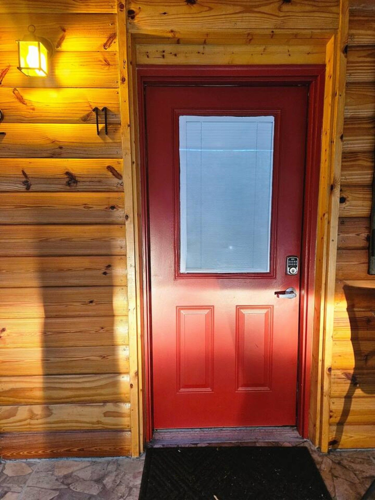 A red door with a window, a doorbell, and a mailbox.