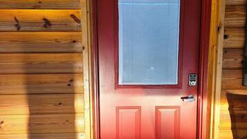 A red door with a window, a doorbell, and a mailbox.