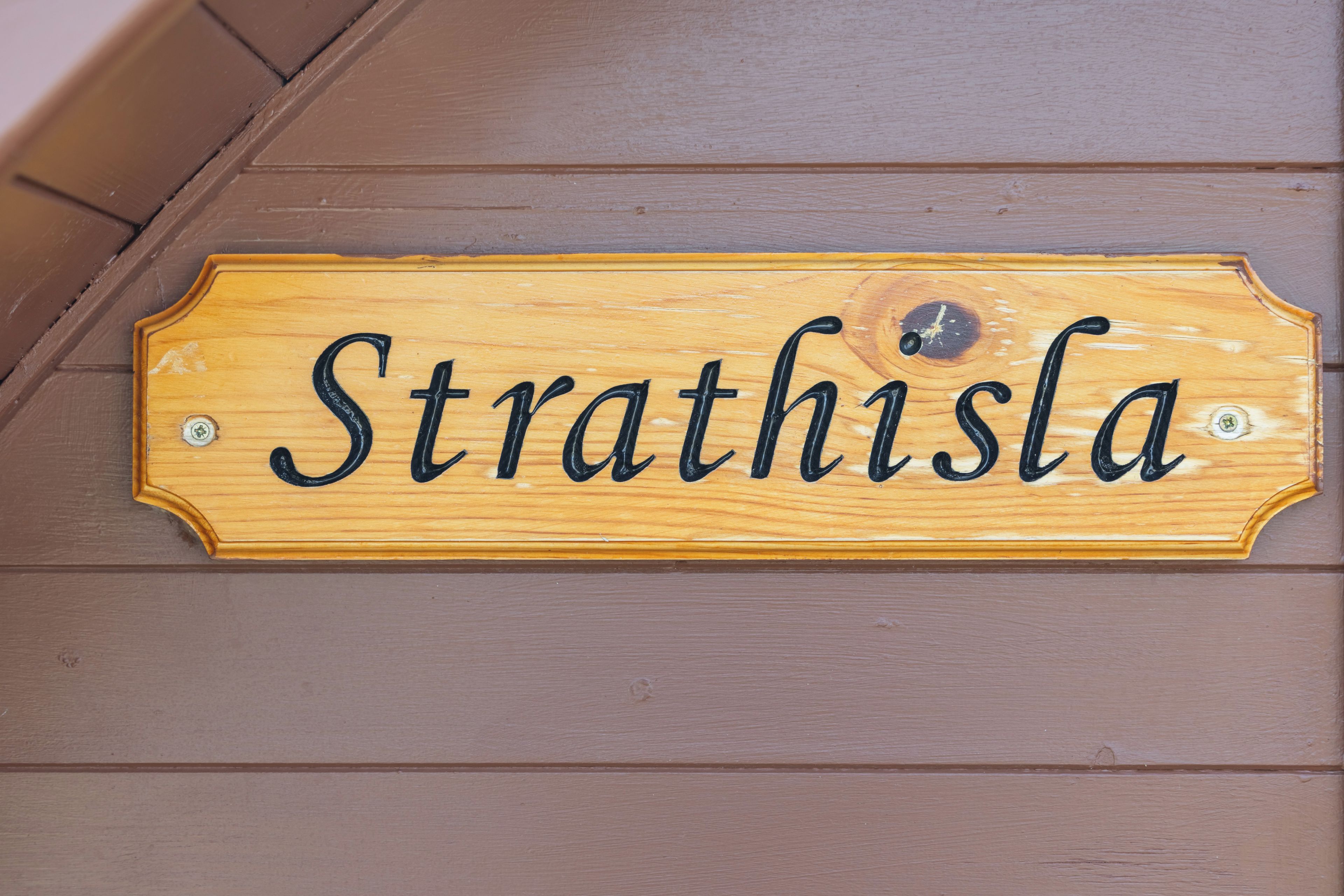 Et træskilt med navnet 'Strathisla' hængende på en væg.