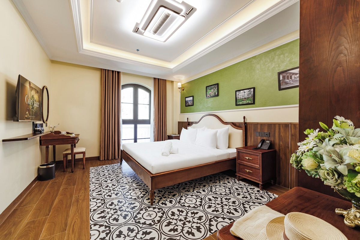 Une chambre d’hôtel avec un grand lit, un bureau, un téléphone et un miroir.