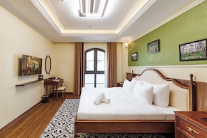 Une chambre d’hôtel avec un grand lit, un bureau avec une chaise, une télévision et des œuvres d’art accrochées aux murs.