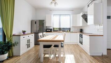 Een moderne keuken met witte kastjes, een houten eettafel en een inbouwoven.