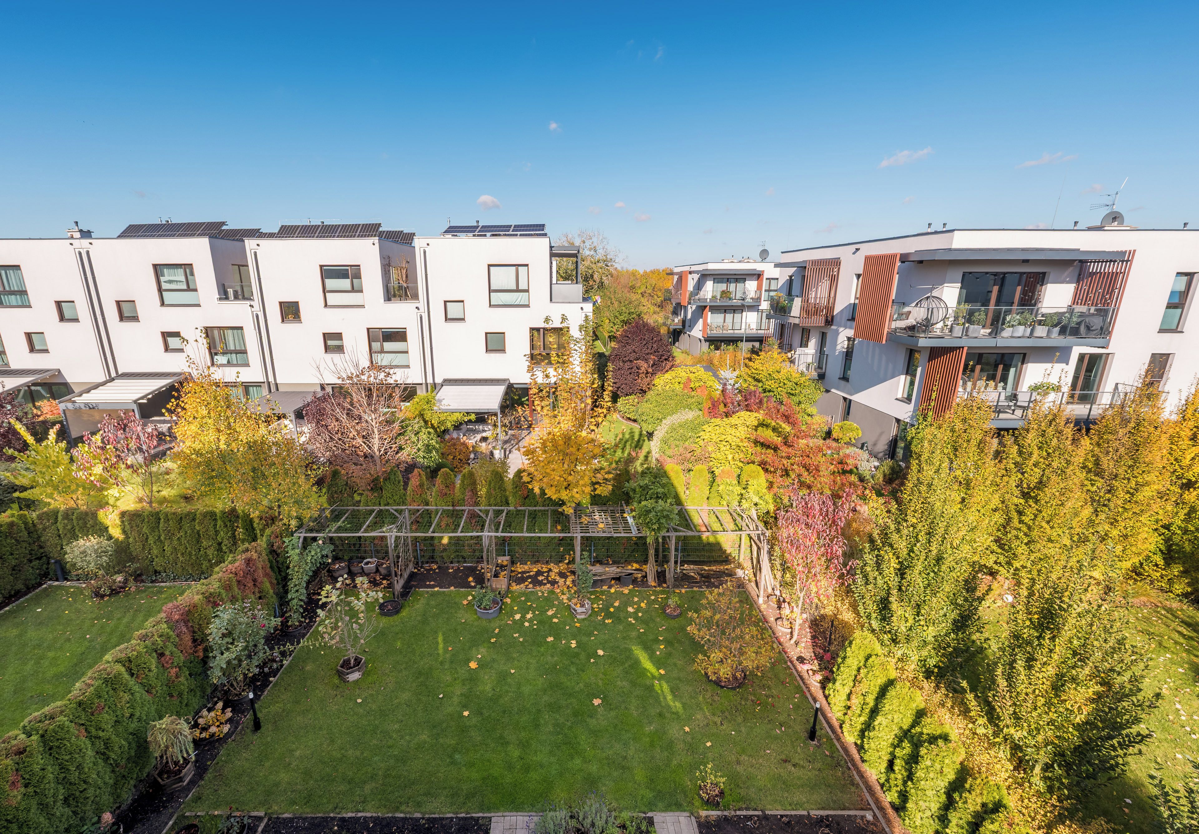 Een modern woongebouw met meerdere balkons, een verzorgde tuin en een heldere lucht.
