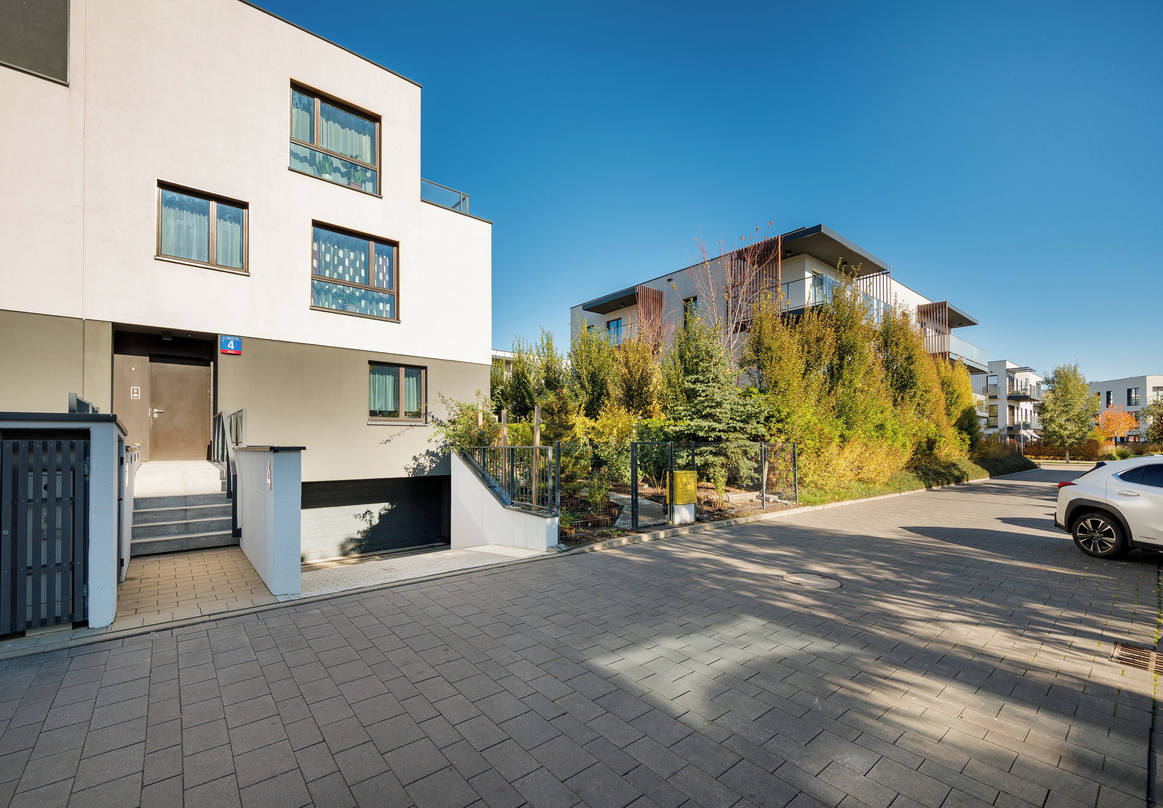 A modern residential building with a flat facade, multiple windows, and a gated entrance.