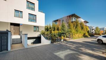 A modern residential building with a flat facade, multiple windows, and a gated entrance.