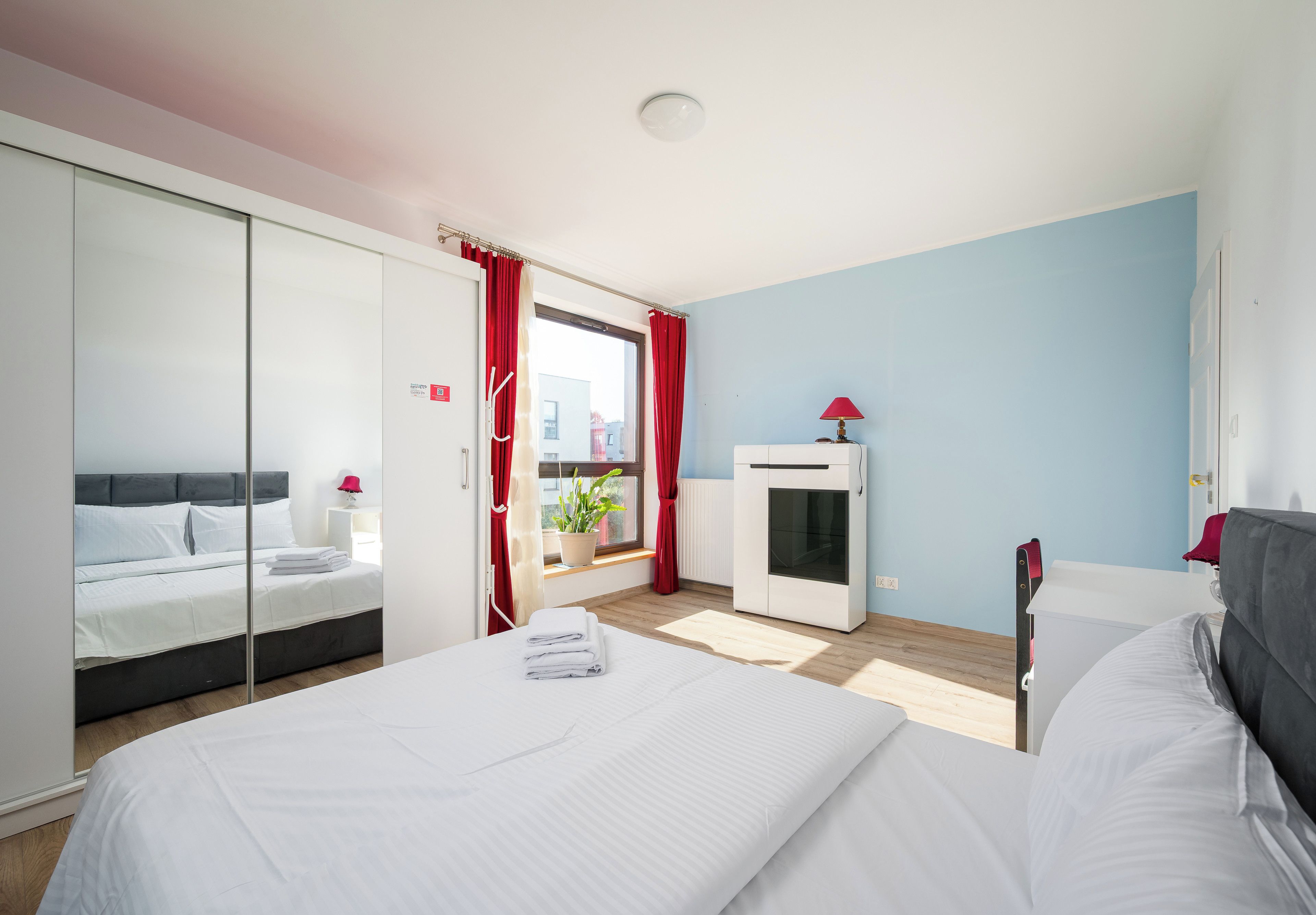 Een moderne slaapkamer met een bed, een kledingkast, een radiator en een raam met gordijnen.