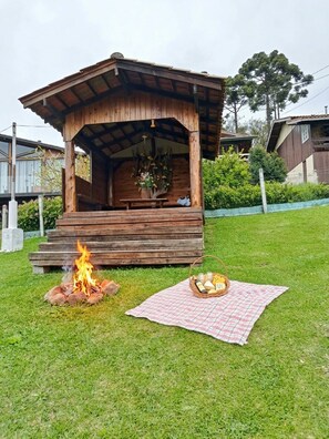 En træpavillon med bålsted og picnicområde.