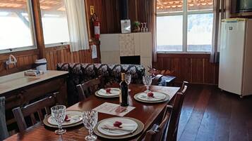 Een houten interieur met een eettafel voor vier personen, een keuken en een open haard.