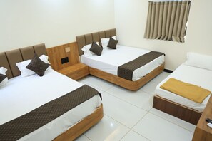 A hotel room with two beds, a wooden headboard, a small wooden cabinet, and a window with curtains. - Hotel Vijay Darshan, Dwarka (Dwarka)
