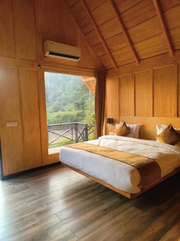 A bedroom with a bed, wooden walls, and a window overlooking a balcony.