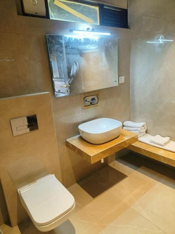 A modern bathroom with a white toilet, a large sink, and a mirror above it.