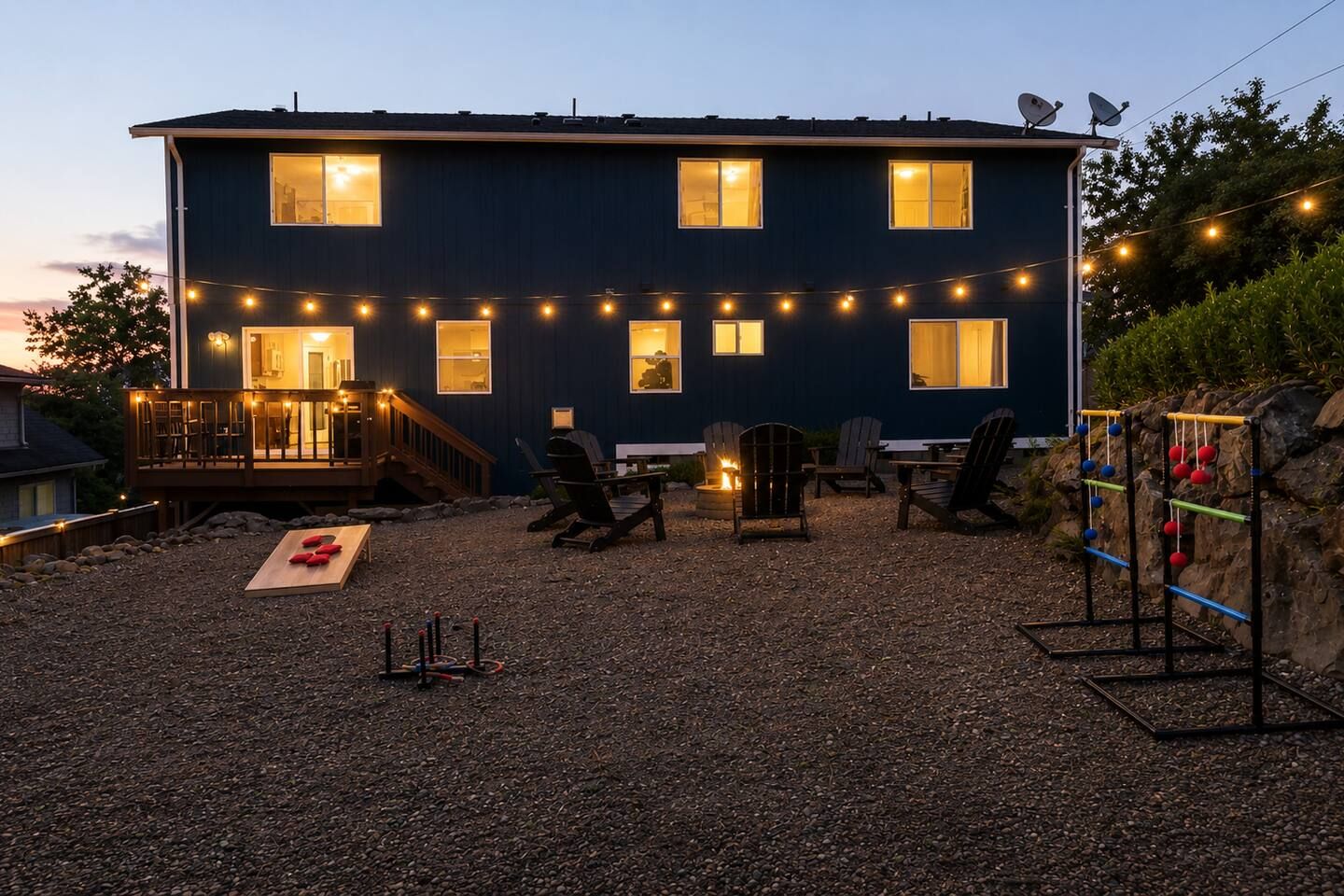 A two-story house with a deck, outdoor seating, and a fire pit.