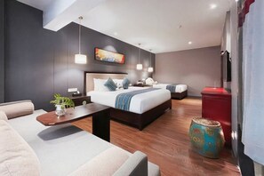 Quarto de hotel moderno com uma cama grande, um sofá, uma mesinha e um vaso decorativo.