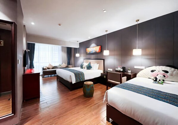 Quarto de hotel com duas camas, um sofá, uma mesa de centro e um vaso decorativo.