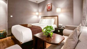 Quarto de hotel com cama, mesa de cabeceira, abajur e uma planta.