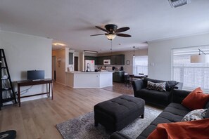 Een moderne woonkamer met een bank, een poef en een televisie op een meubel.
