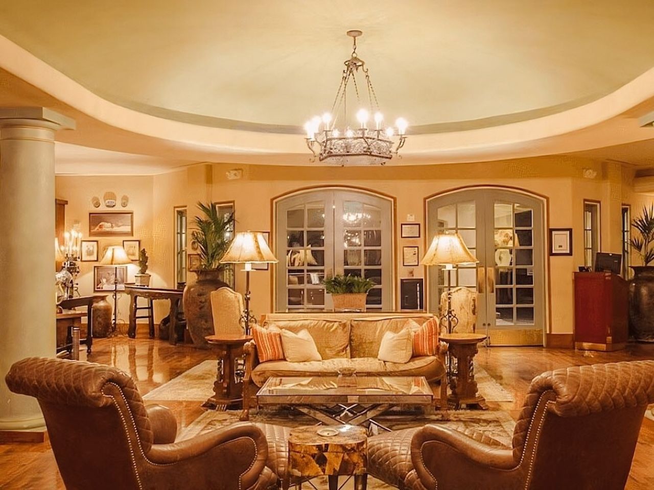 Een ruime woonkamer met een grote bank, twee fauteuils, een salontafel en een kroonluchter.